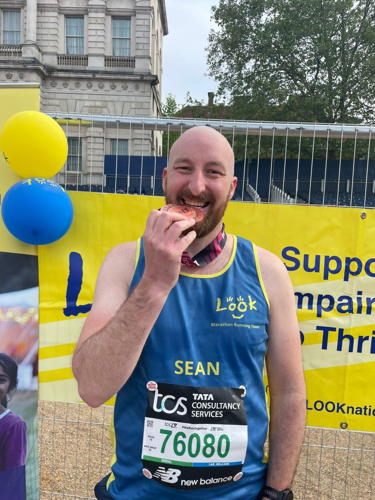 Runner Sean biting down on his 2027 marathon medal